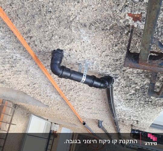 צינור שחור מחובר לקיר עם תושבת מתכת